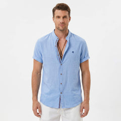 Three quarter view of man in light blue linen look stand collar shirt and crinkle drawstring shorts