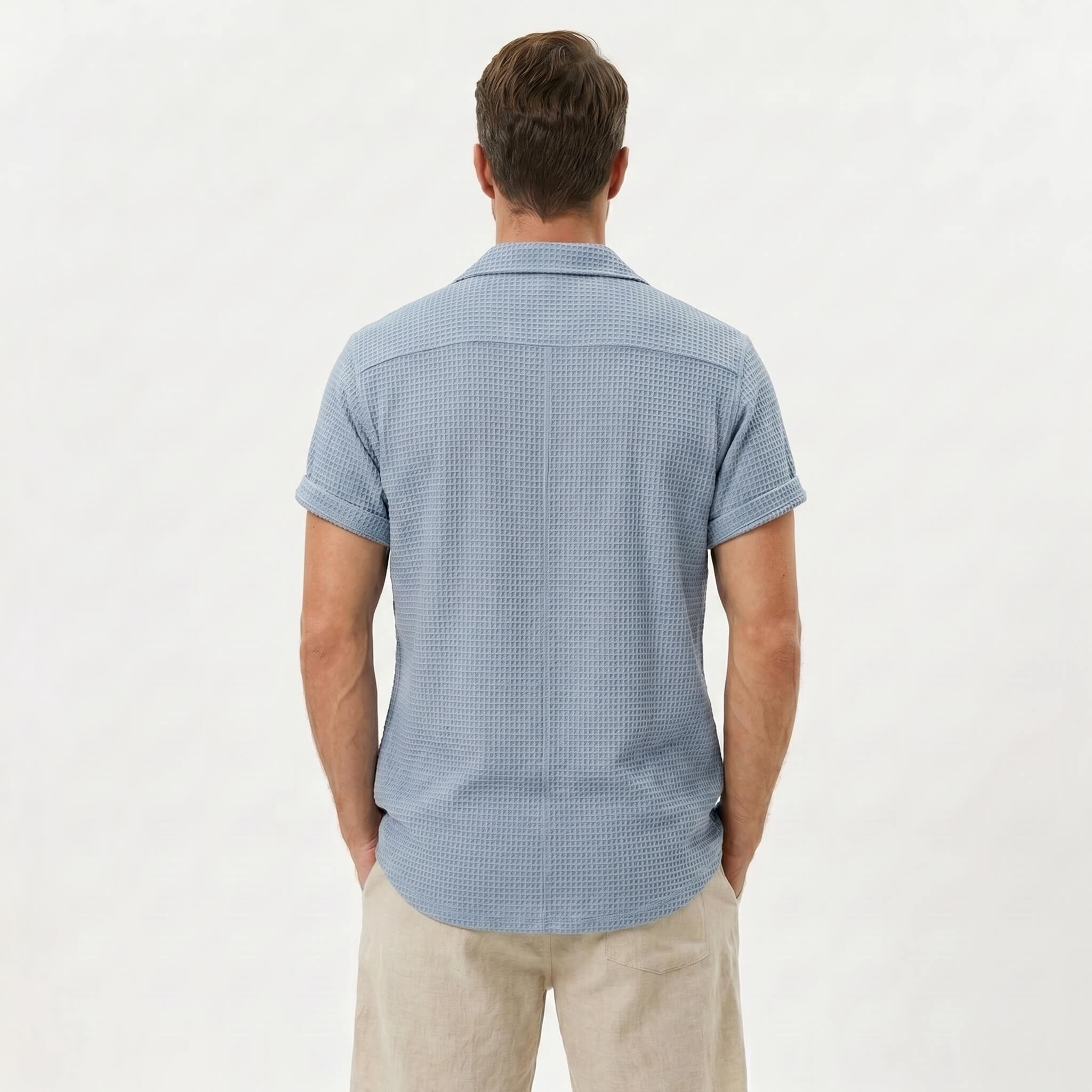 Back view of man wearing light blue textured Cuban shirt and linen cotton drawstring shorts