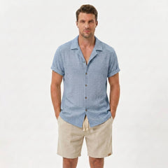 Man wearing light blue textured Cuban shirt and linen cotton drawstring shorts front view on plain background