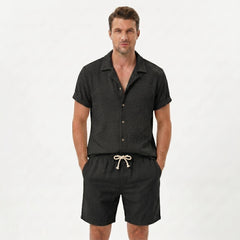 Man in light blue textured Cuban shirt and linen drawstring shorts in sunny outdoor summer scene