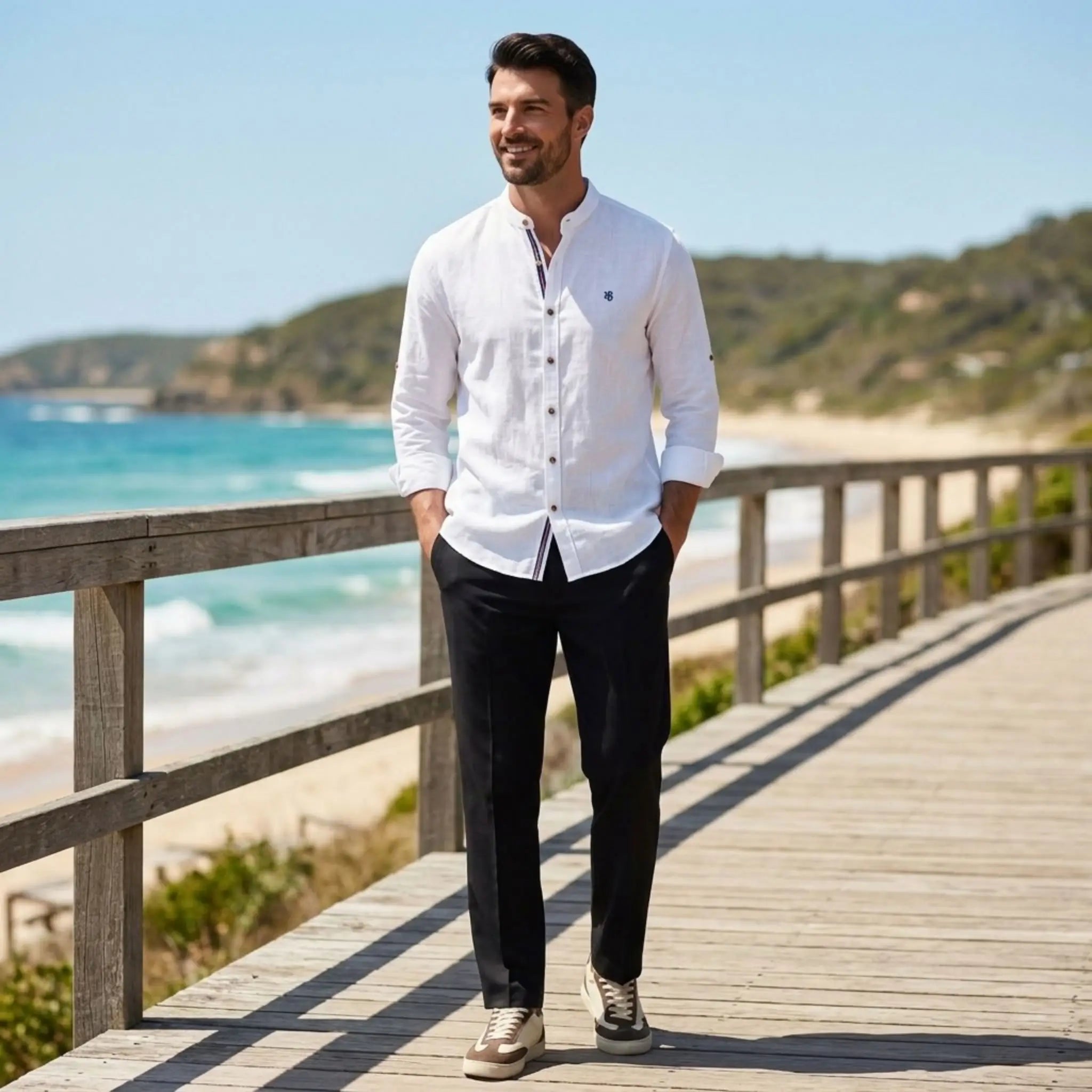 Man wearing white linen stand collar shirt and black slim fit trousers on sunny beach boardwalk