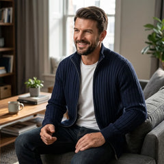 Man in navy cable knit zip sweater seated indoors