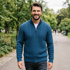 Man wearing teal blue cable knit quarter-zip sweater on a leafy street