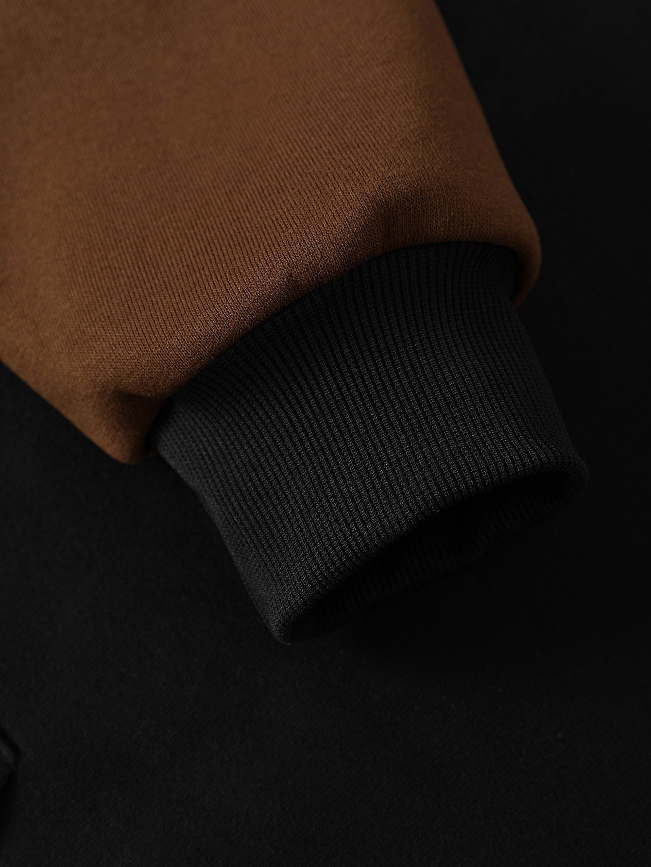 Coffee hoodie sleeve with black ribbed cuff, close-up