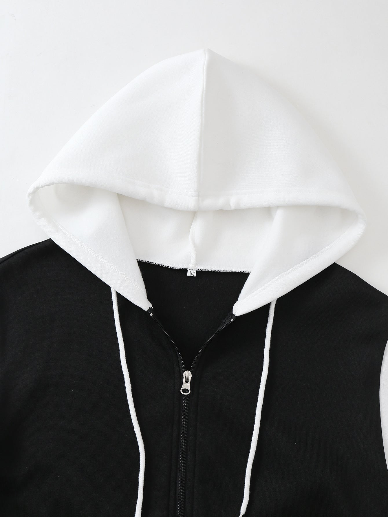 White hood with drawstrings and black full-zip front, close-up