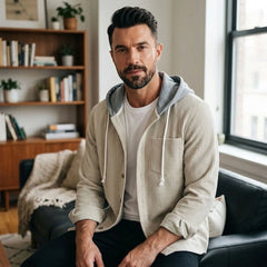 Man in beige corduroy hooded shirt jacket seated in a living room