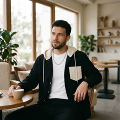 Man in black corduroy hooded shirt jacket seated in a cafe