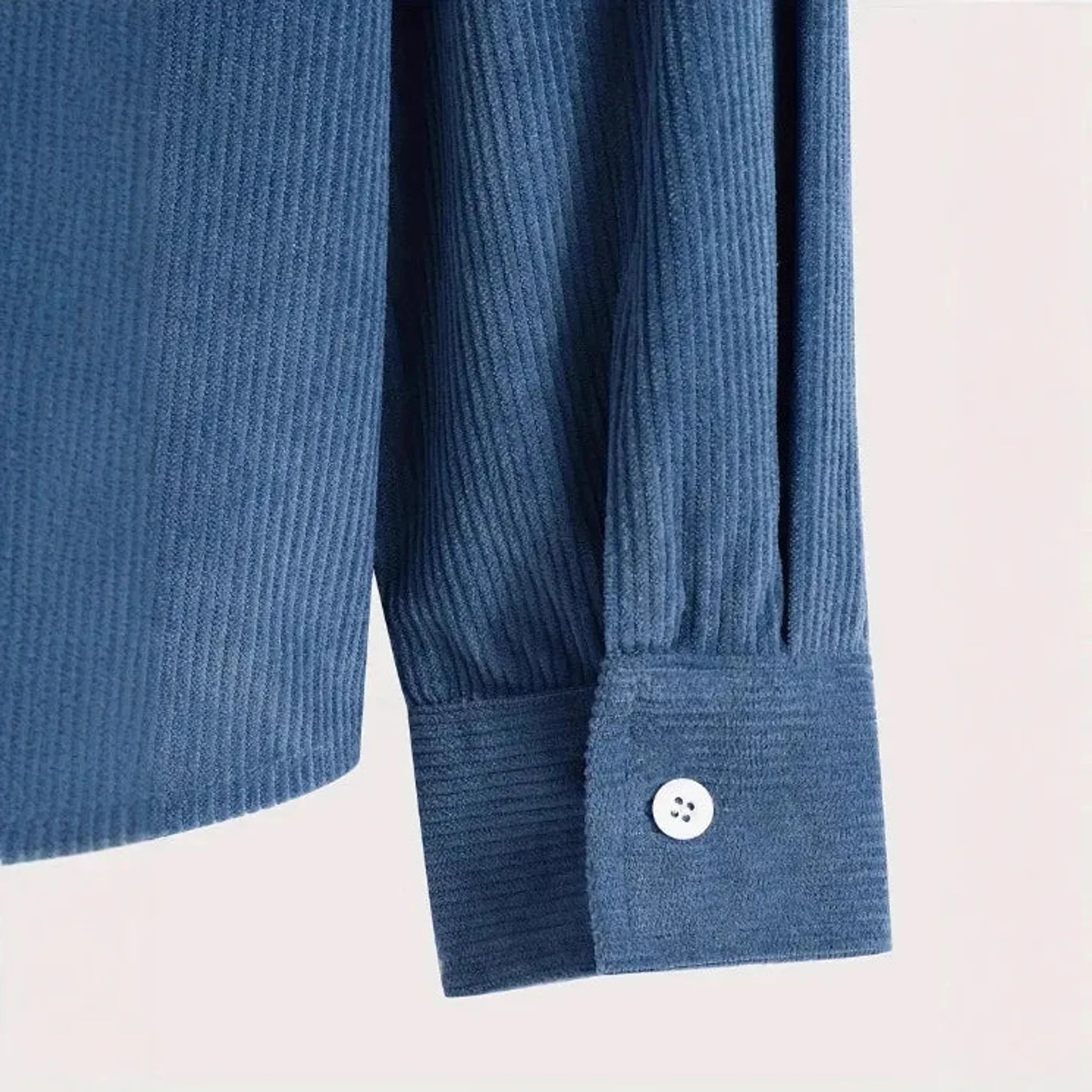 Denim blue corduroy shirt jacket, close-up of cord texture and button cuff
