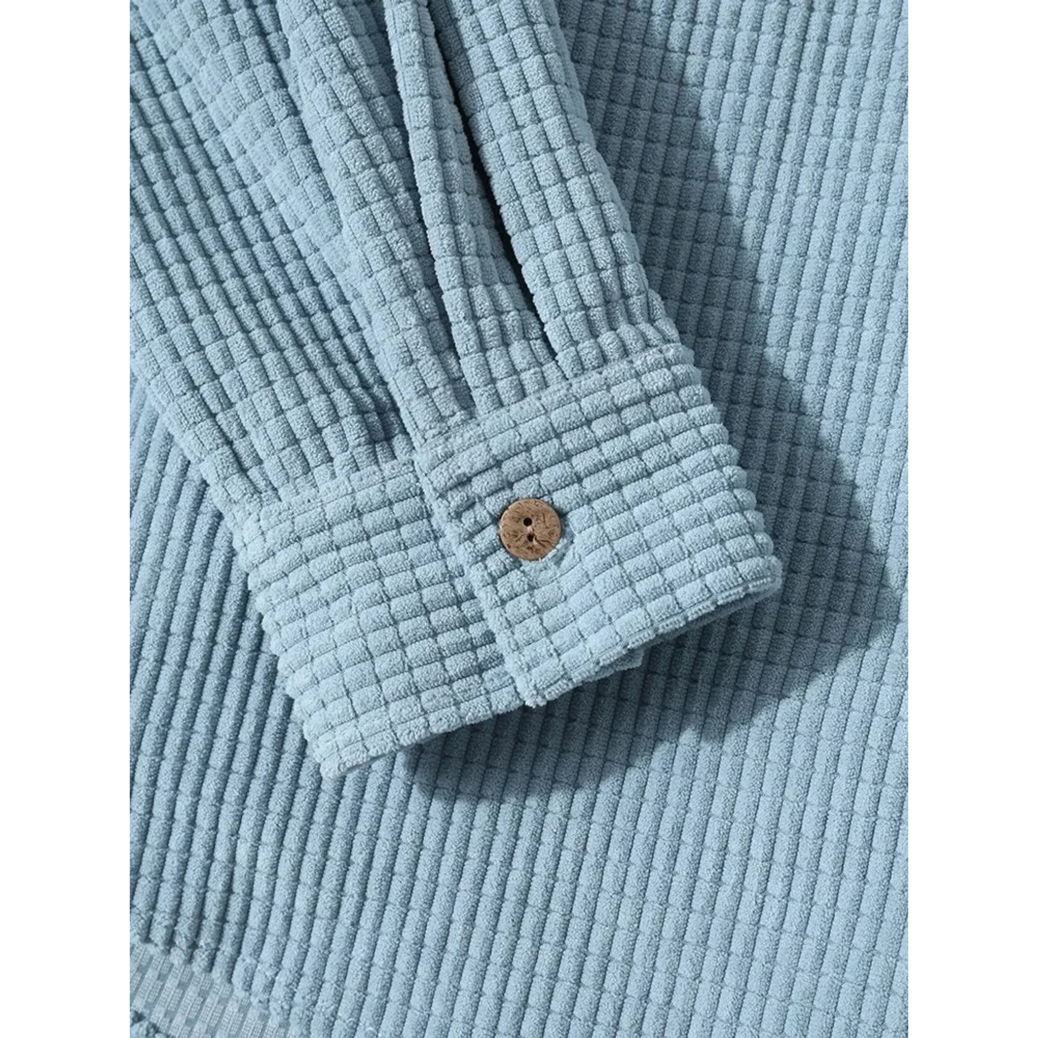 Close-up of the buttoned cuff on the light blue corduroy jacket