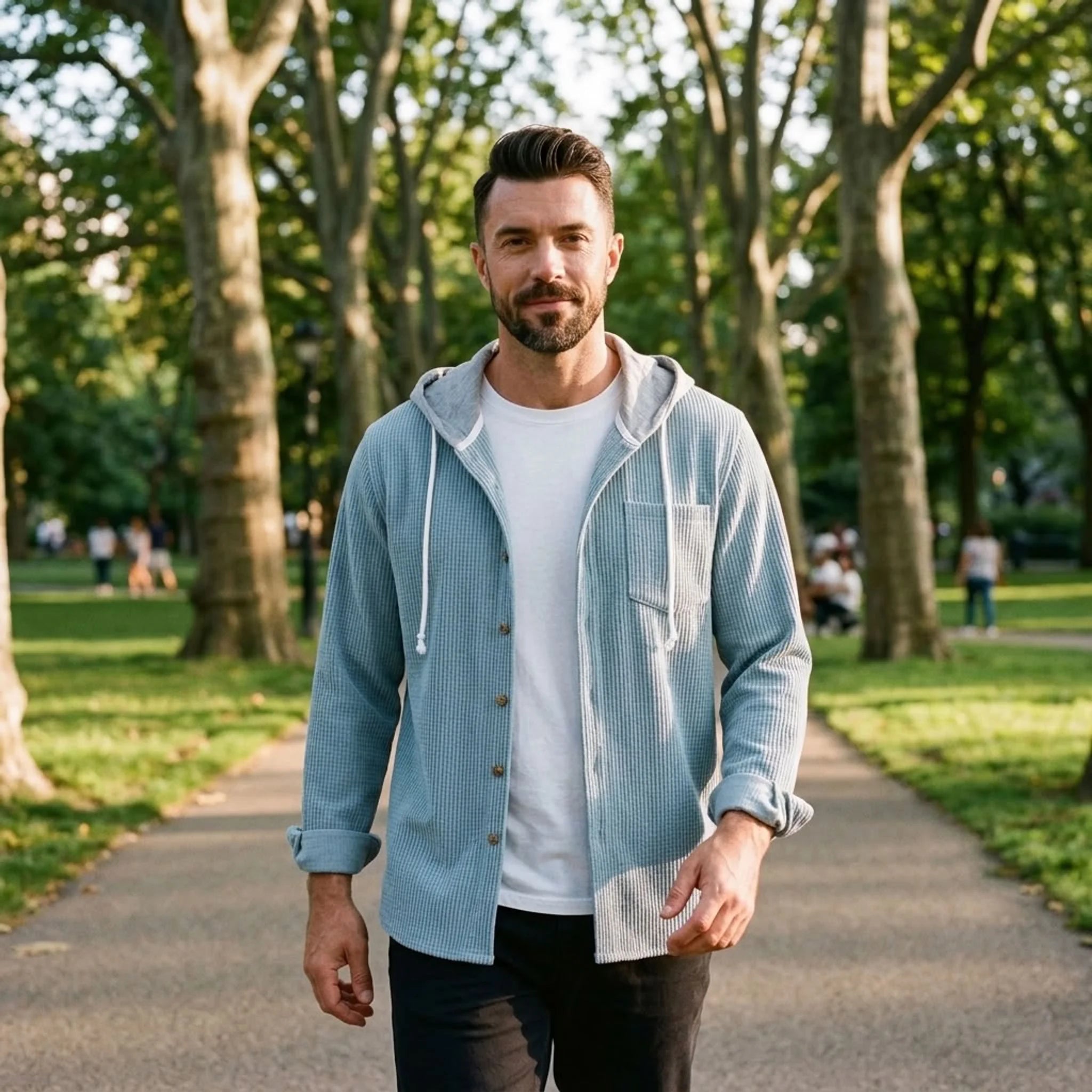 Man in light blue corduroy hooded shirt jacket walking in a park