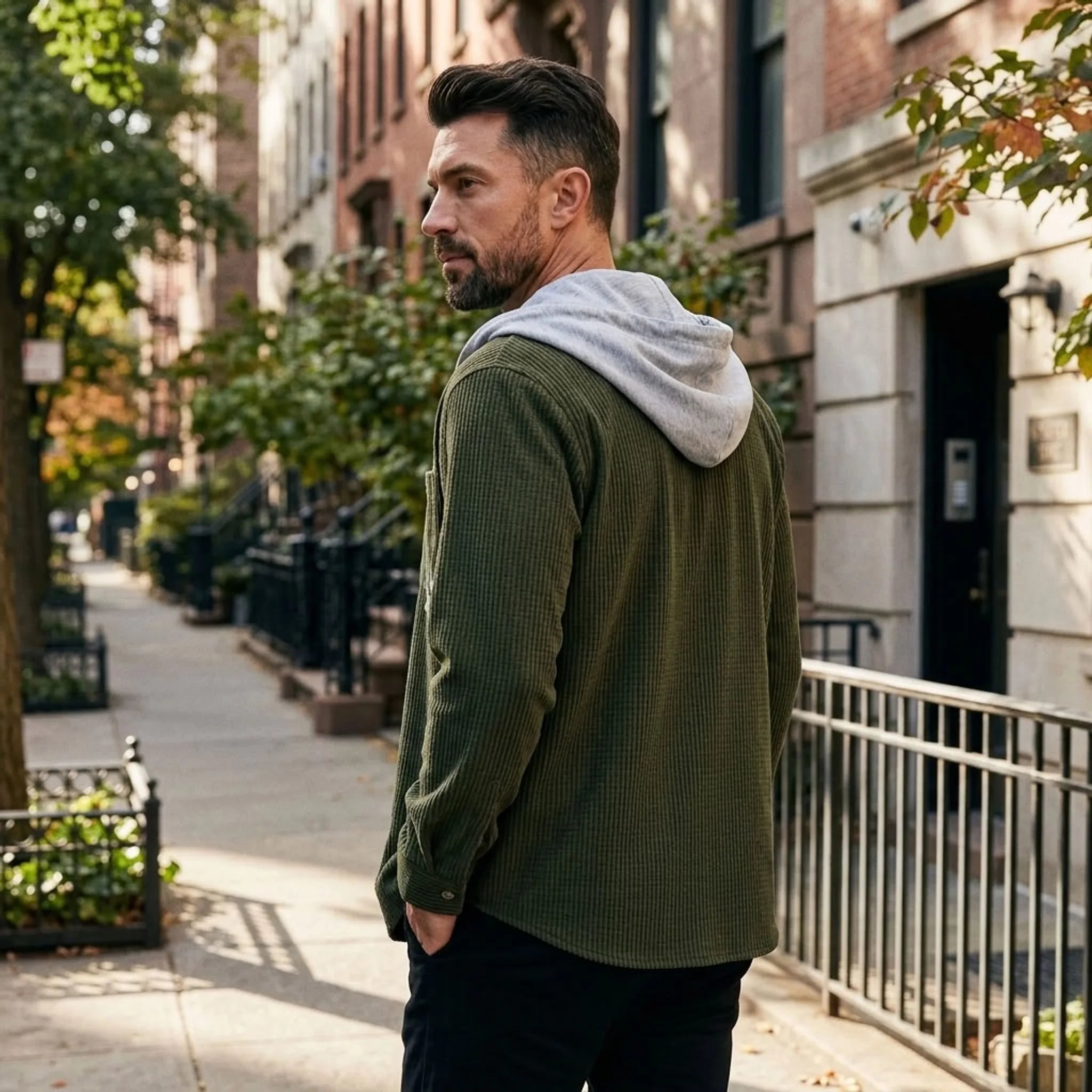 Man in olive green corduroy hooded shirt jacket on a city street