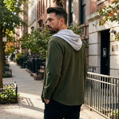 Man in olive green corduroy hooded shirt jacket on a city street