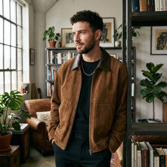 Man wearing camel faux suede zip jacket by a bookshelf indoors