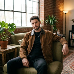 Man in camel faux suede zip jacket seated in a loft living room
