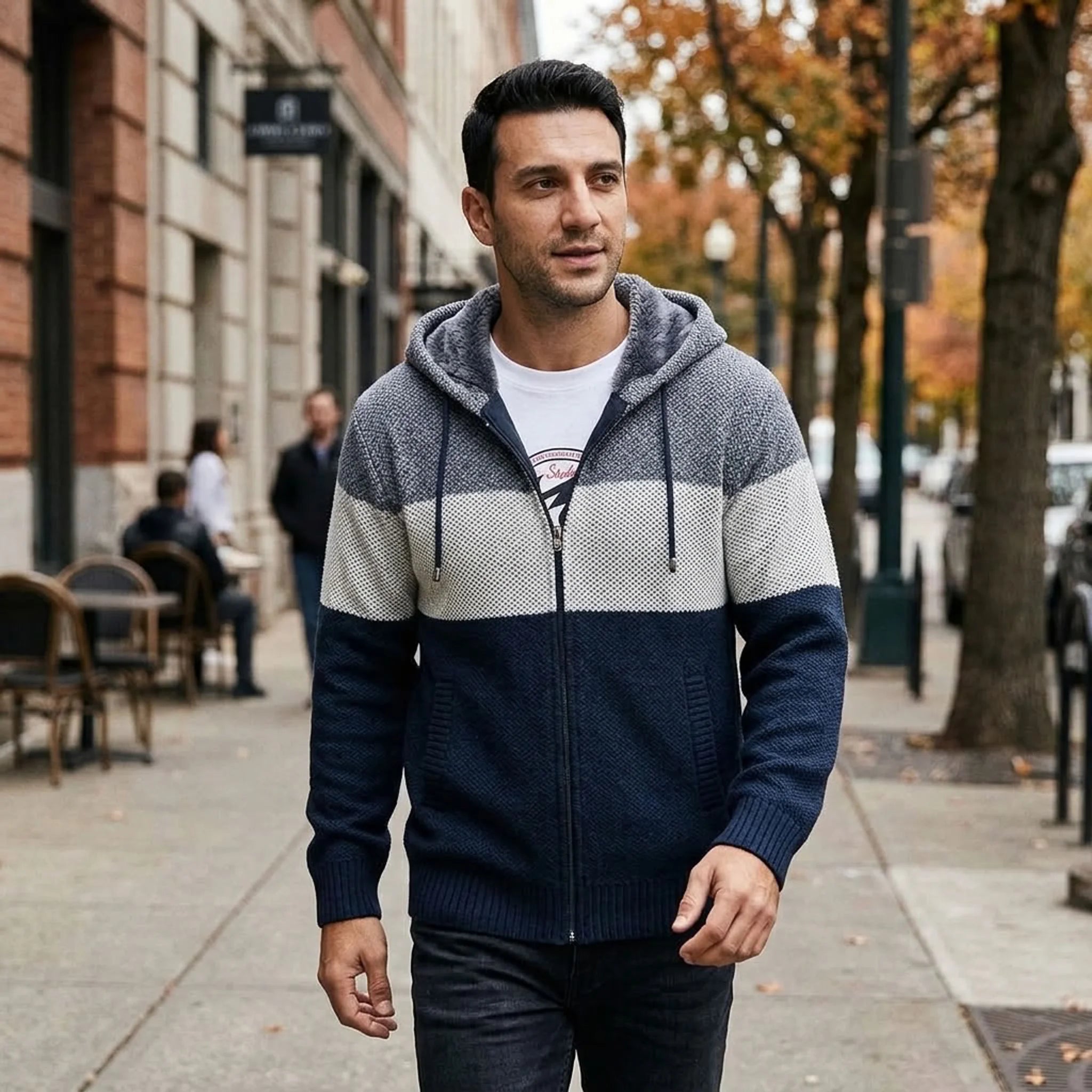 Man in navy knit zip hoodie walking on an autumn city street