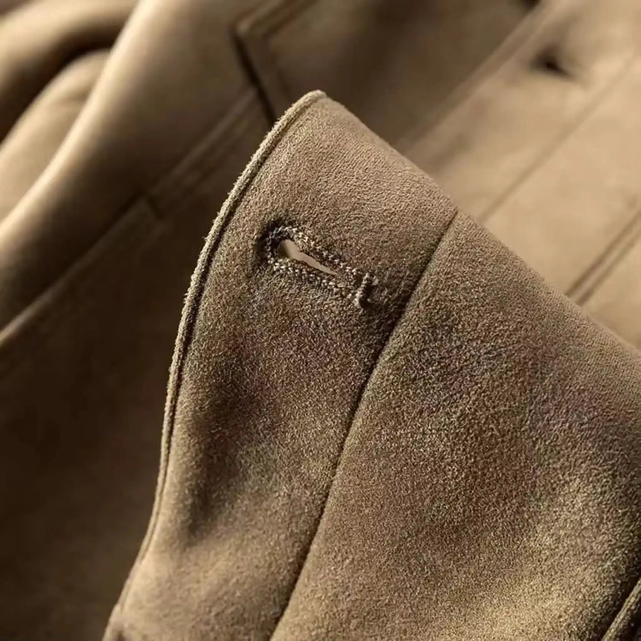 Close-up of the buttoned cuff on the sleeve of a khaki suede-look trucker jacket