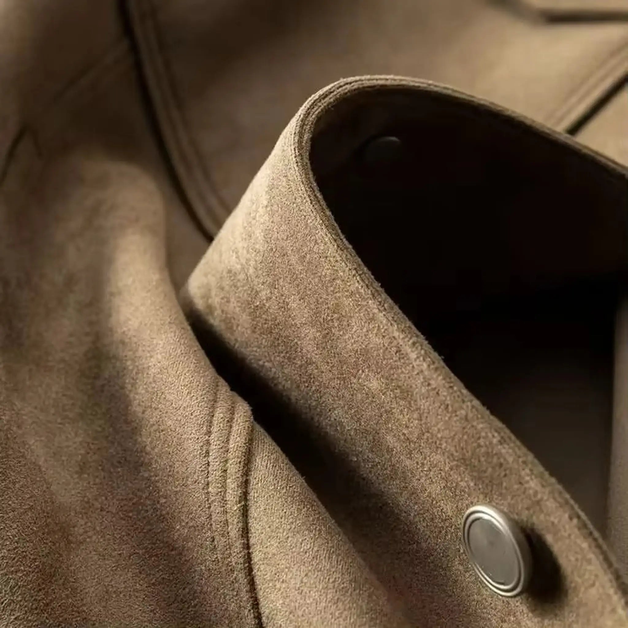 Close-up of the collar edge and metal button on a khaki suede-look trucker jacket