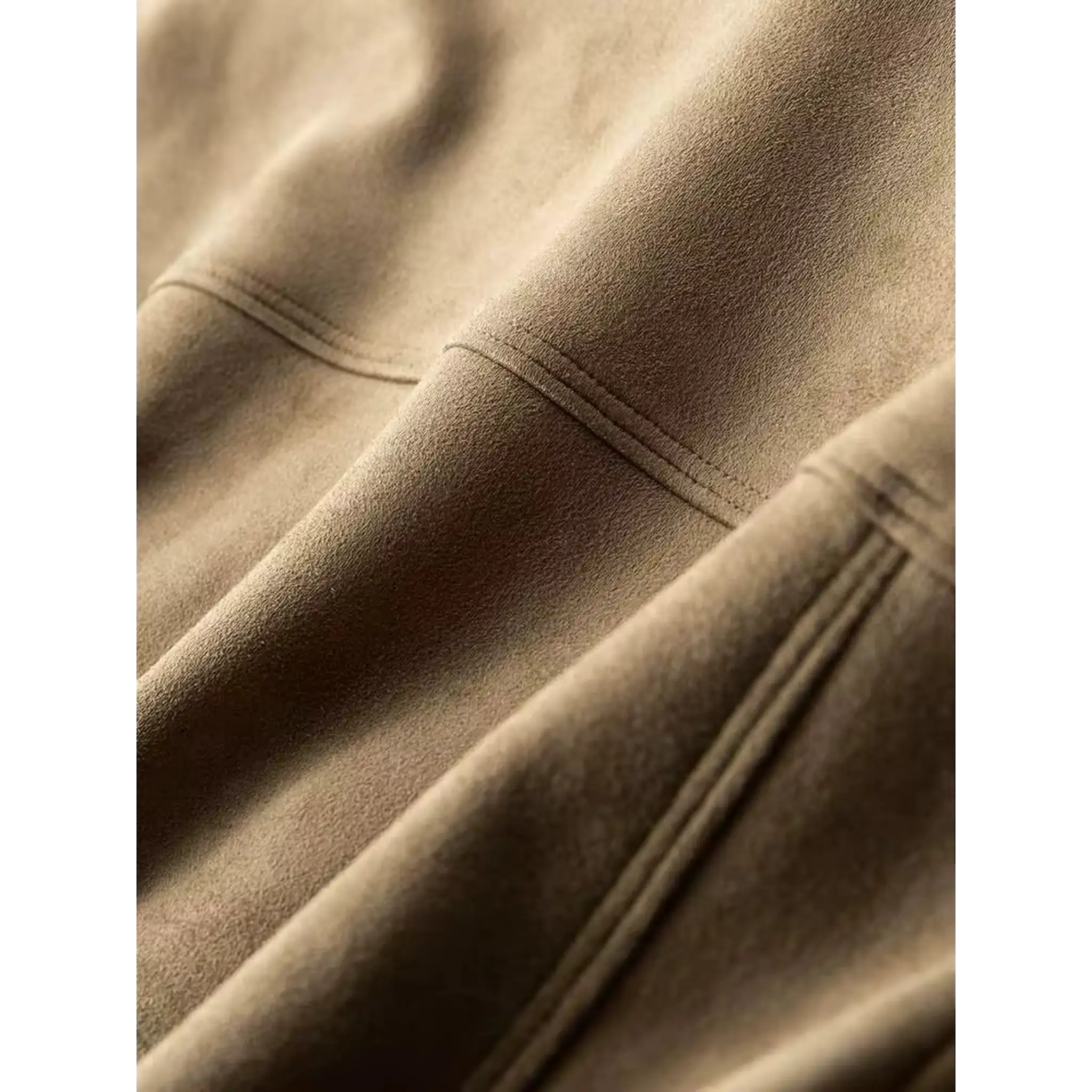 Close-up of the stitched panel seams on a khaki suede-look trucker jacket