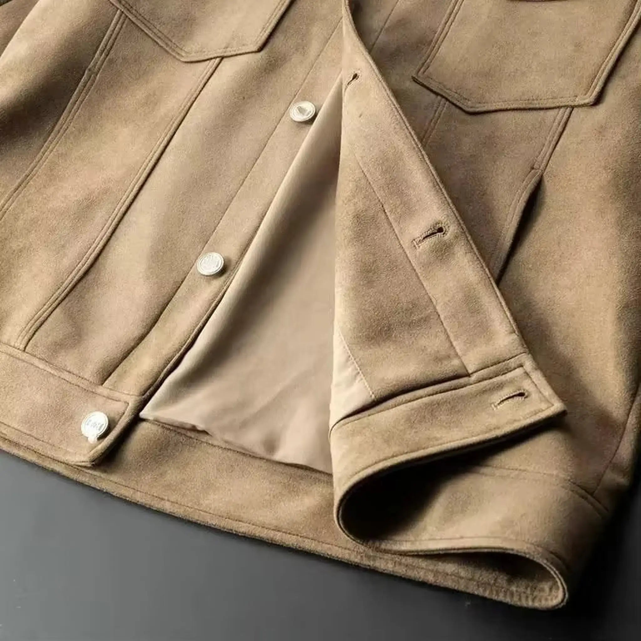 Close-up of the button front, chest pocket and buttoned cuff of a khaki suede-look trucker jacket