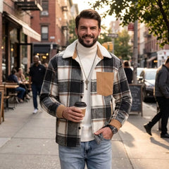 Man in black plaid shirt jacket holding coffee on a city sidewalk