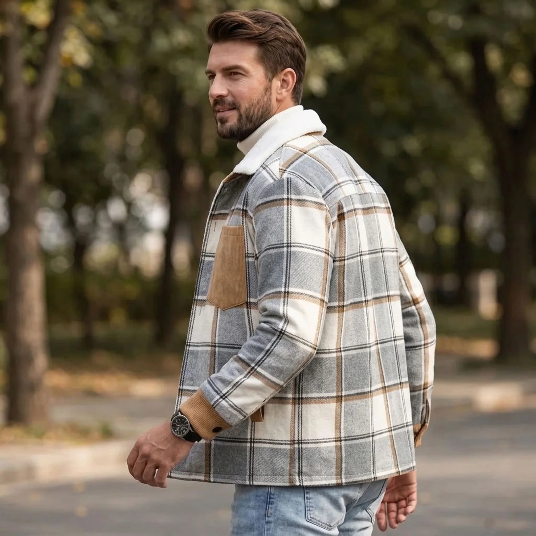 Man walking in a park wearing a light grey plaid shirt jacket