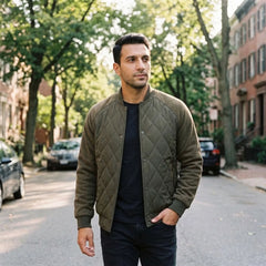 Man wearing olive quilted bomber jacket on a tree-lined street
