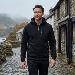 MannerCo black fleece hoodie worn walking a misty cobblestone village street
