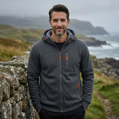 MannerCo dark grey fleece hoodie worn outdoors on a rugged coastline