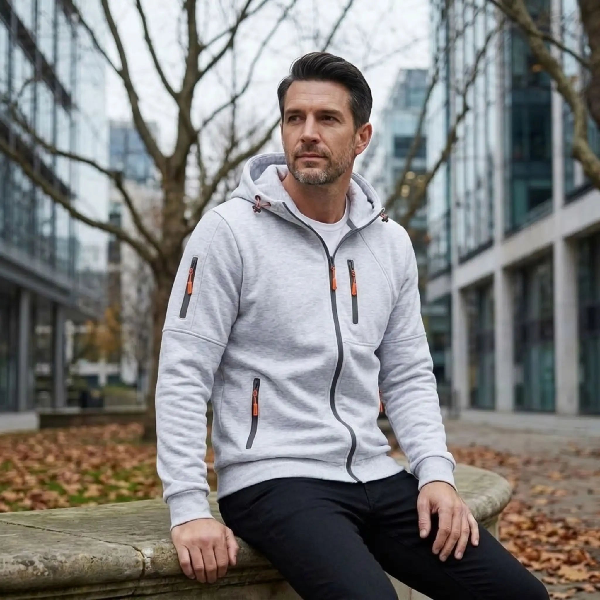 MannerCo white fleece hoodie, man seated outdoors in a city on an autumn day