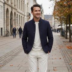 MannerCo navy blue wool overcoat with stand collar worn by man walking on European cobblestone street