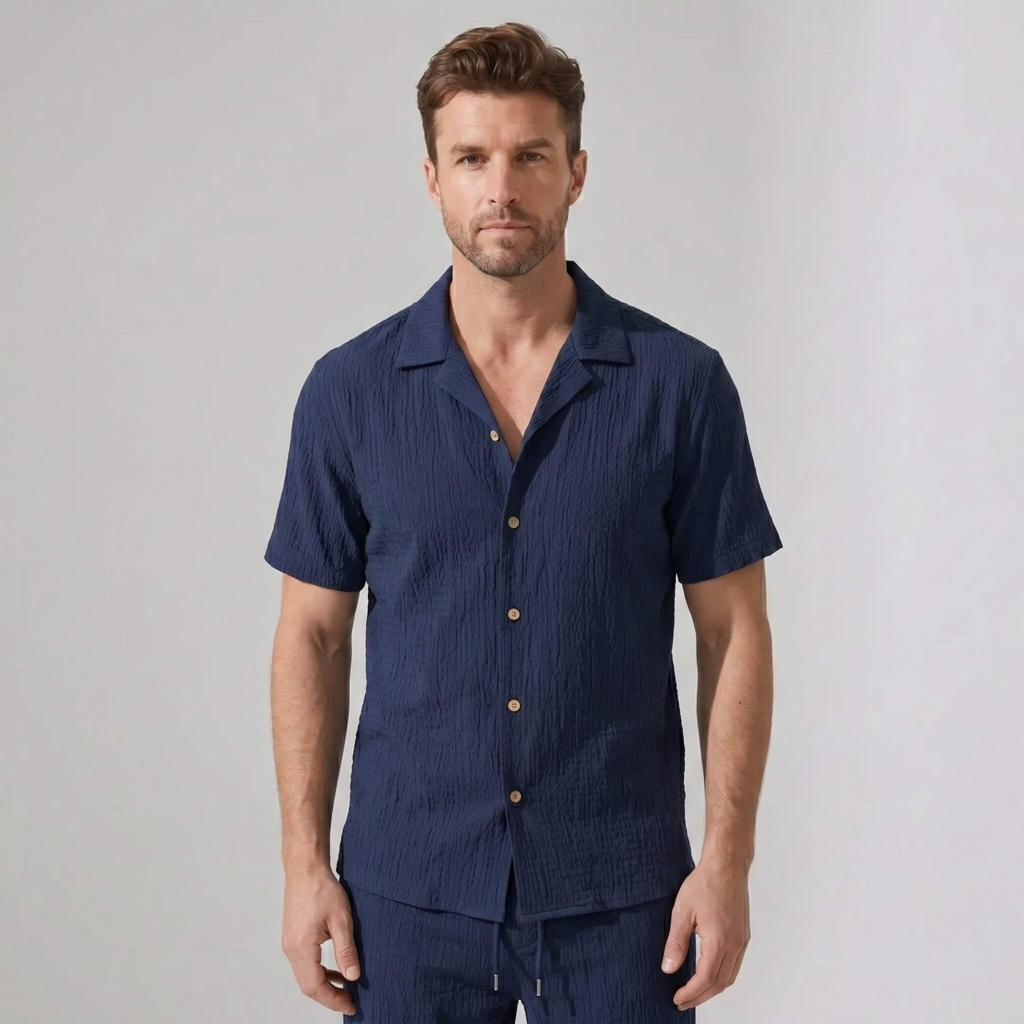 Three quarter view of man in navy crinkled textured shirt and straight leg pants