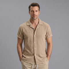 Three quarter view of man in navy geometric jacquard shirt and crinkle shorts on plain background