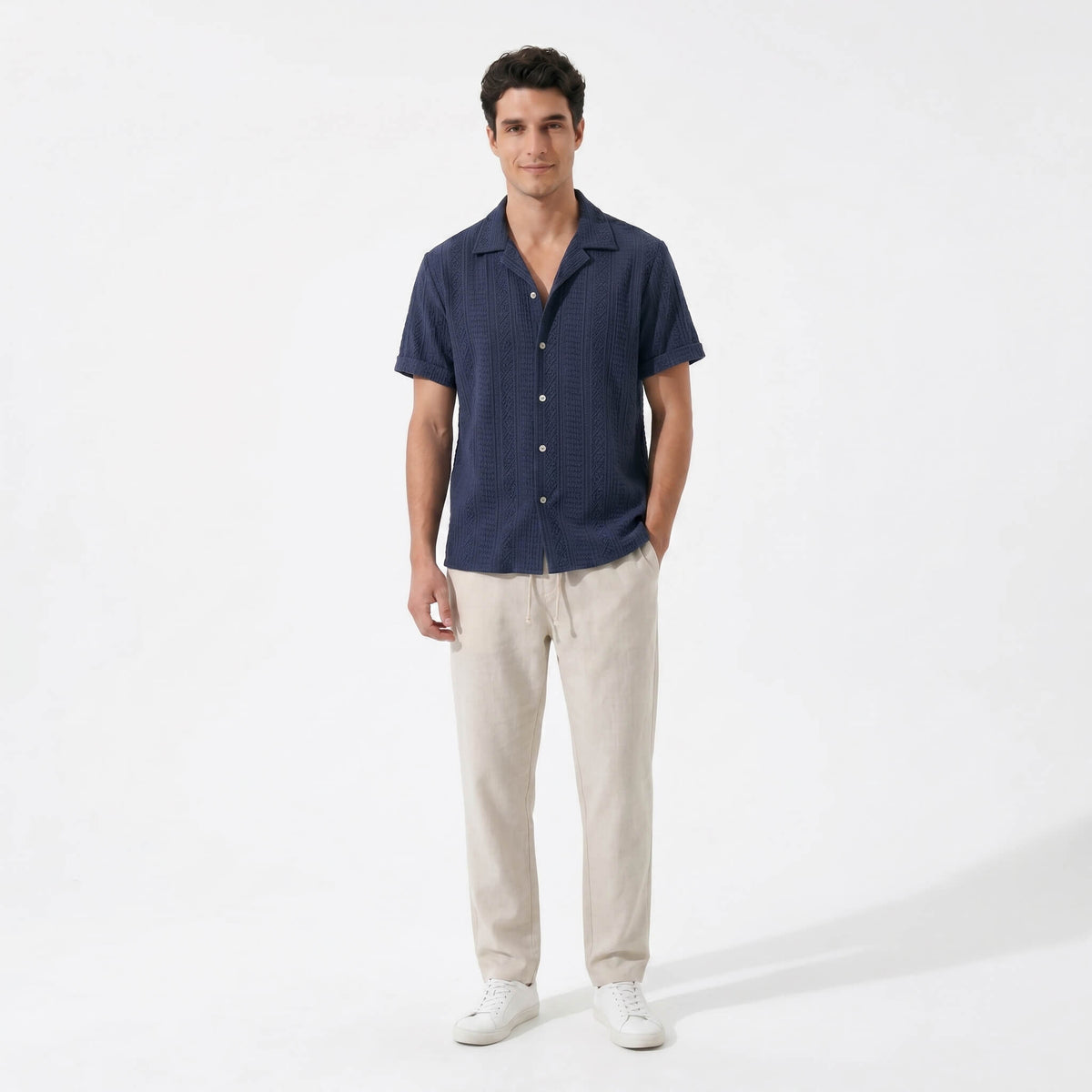 Man wearing a navy geometric jacquard button up shirt and straight leg linen pants front view on white background