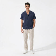 Man wearing a navy geometric jacquard button up shirt and straight leg linen pants front view on white background