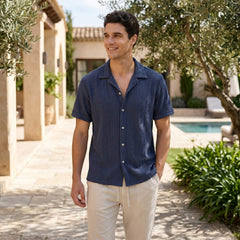 Man wearing navy geometric jacquard button up shirt and linen pants in outdoor lifestyle setting