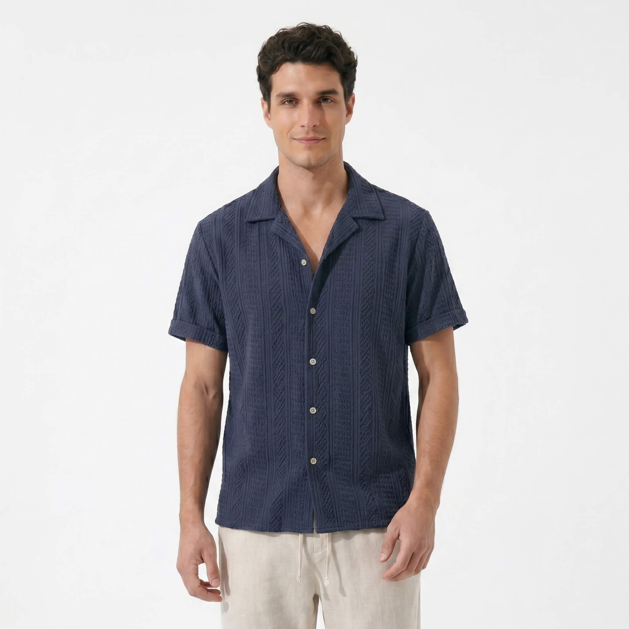 Three quarter view of man in navy geometric jacquard shirt and linen pants on white background