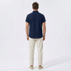 Back view of man wearing navy linen rayon blend utility shirt and straight leg linen pants