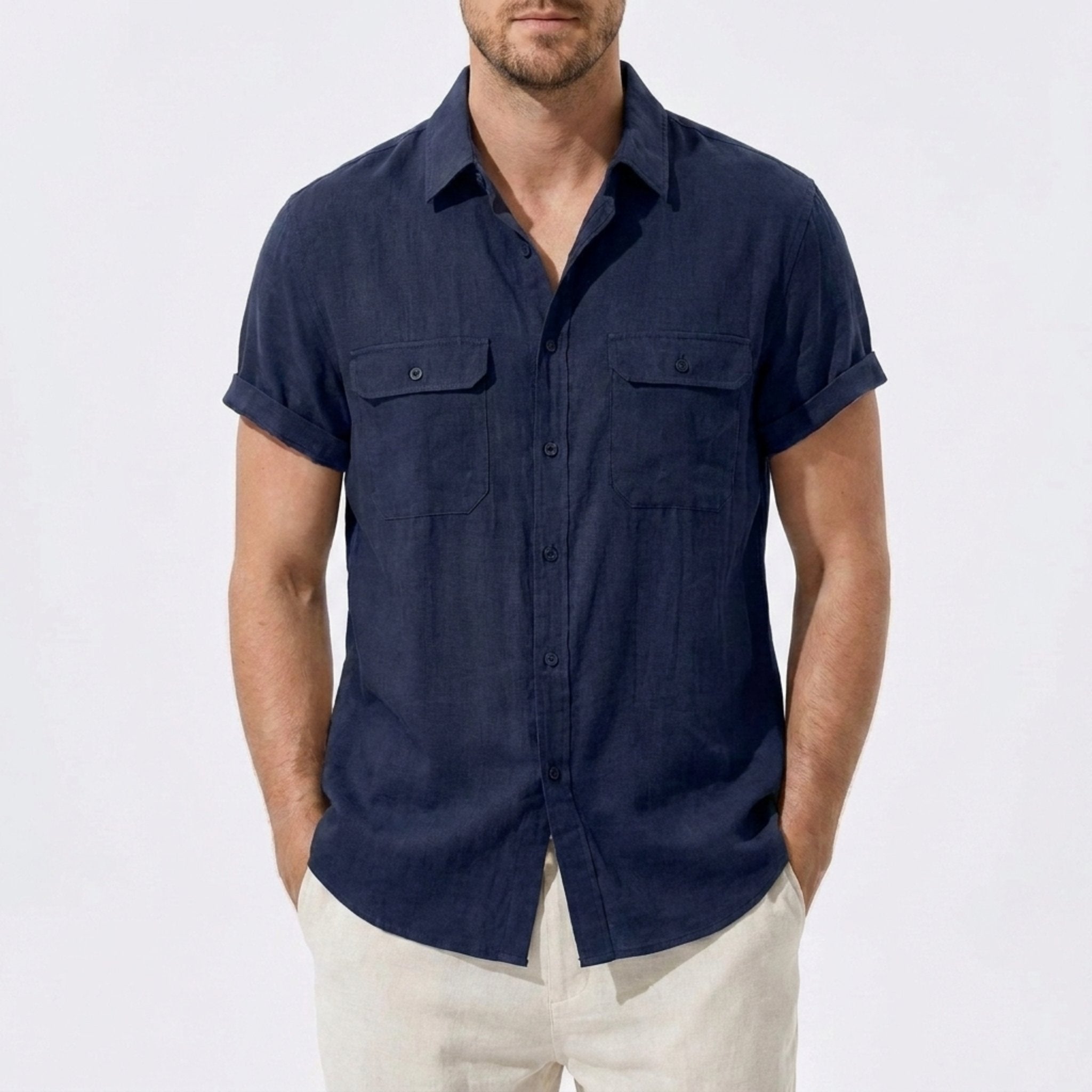 Three quarter view of man in navy linen rayon blend utility shirt and linen pants on plain background