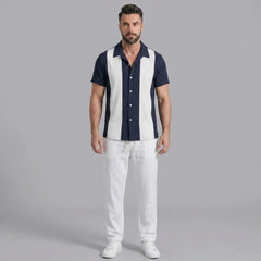 Man wearing a navy patchwork cotton bowling shirt and straight leg linen pants front view on plain background