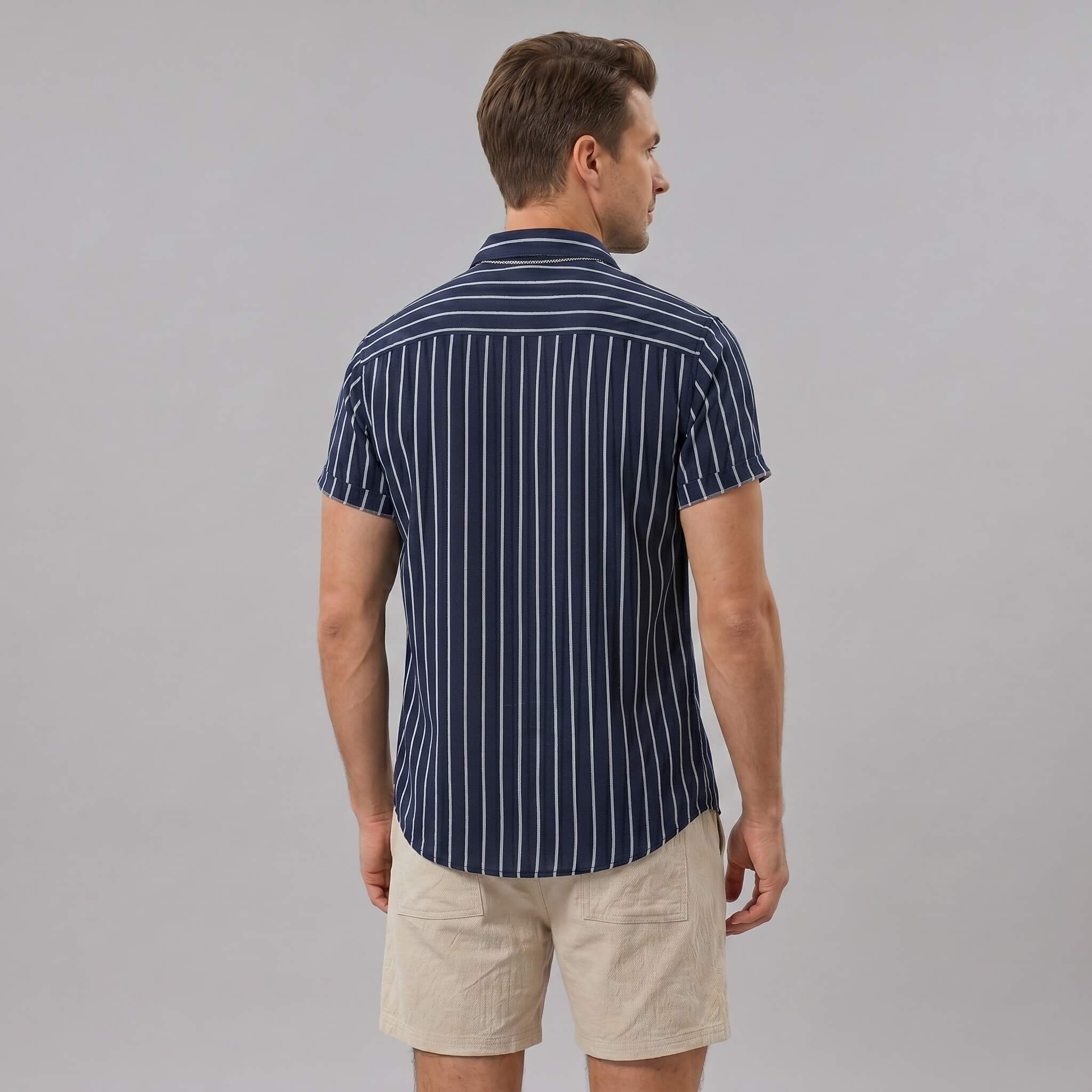 Back view of man wearing navy striped cotton blend shirt and crinkle textured drawstring shorts