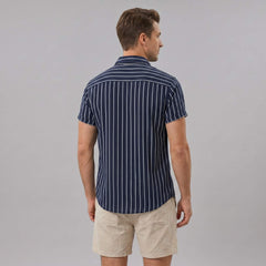 Back view of man wearing navy striped cotton blend shirt and crinkle textured drawstring shorts