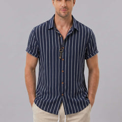 Three quarter view of man in navy striped cotton blend shirt and crinkle drawstring shorts on plain background