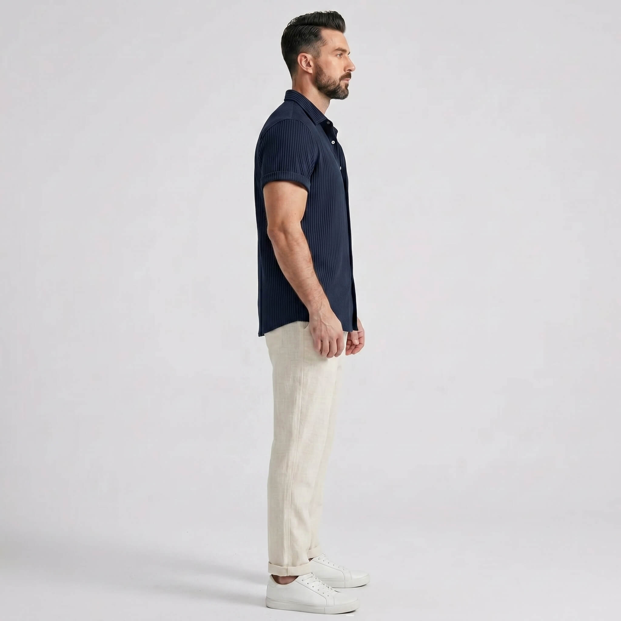 Man wearing a navy waffle button up shirt and straight leg linen pants front view on plain background