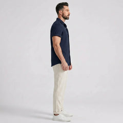 Man wearing a navy waffle button up shirt and straight leg linen pants front view on plain background