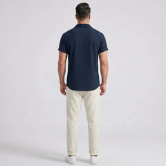 Side view of man in navy waffle button up shirt and straight leg linen pants