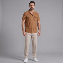 Man wearing an orange linen Cuban collar shirt and slim fit tapered trousers front view on plain background