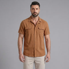 Three quarter view of man in orange linen Cuban collar shirt and slim fit tapered trousers