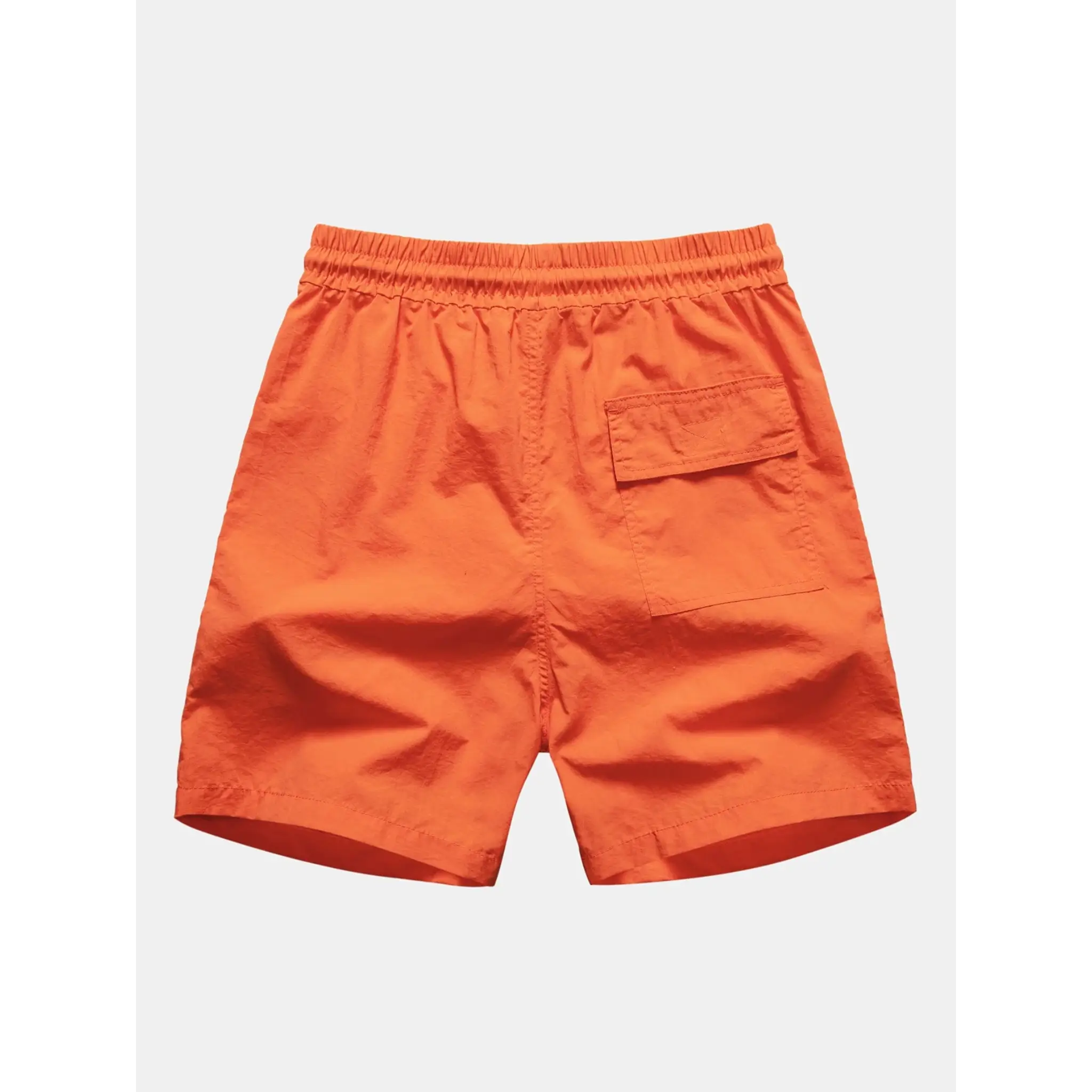 Side view of man in orange palm tree tropical print shirt and swim shorts on plain background