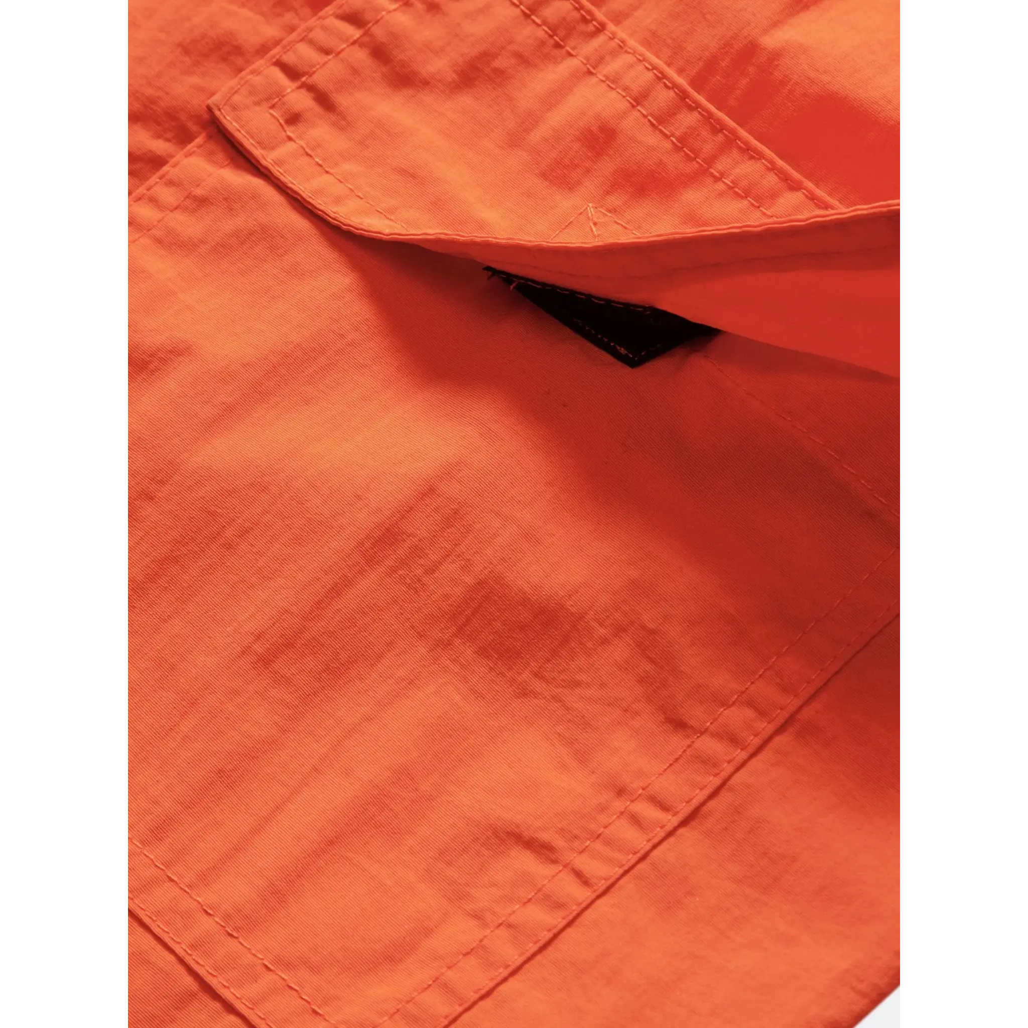 Three quarter view of man in orange palm tree tropical print shirt and swim shorts on plain background