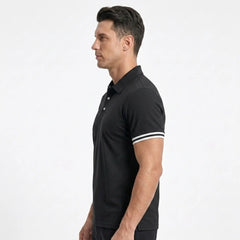 Man wearing MannerCo black polo shirt with white stripe sleeve detail, side view
